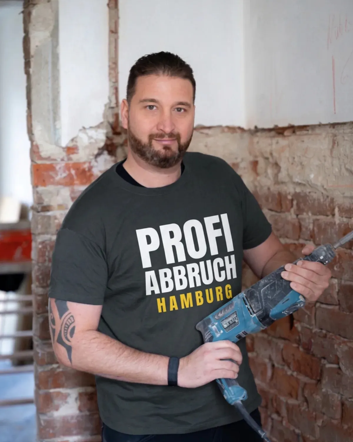 Timo Brandt, Inhaber von Profi Abbruch Hamburg, mit Abbruchhammer auf einer entkernten Baustelle